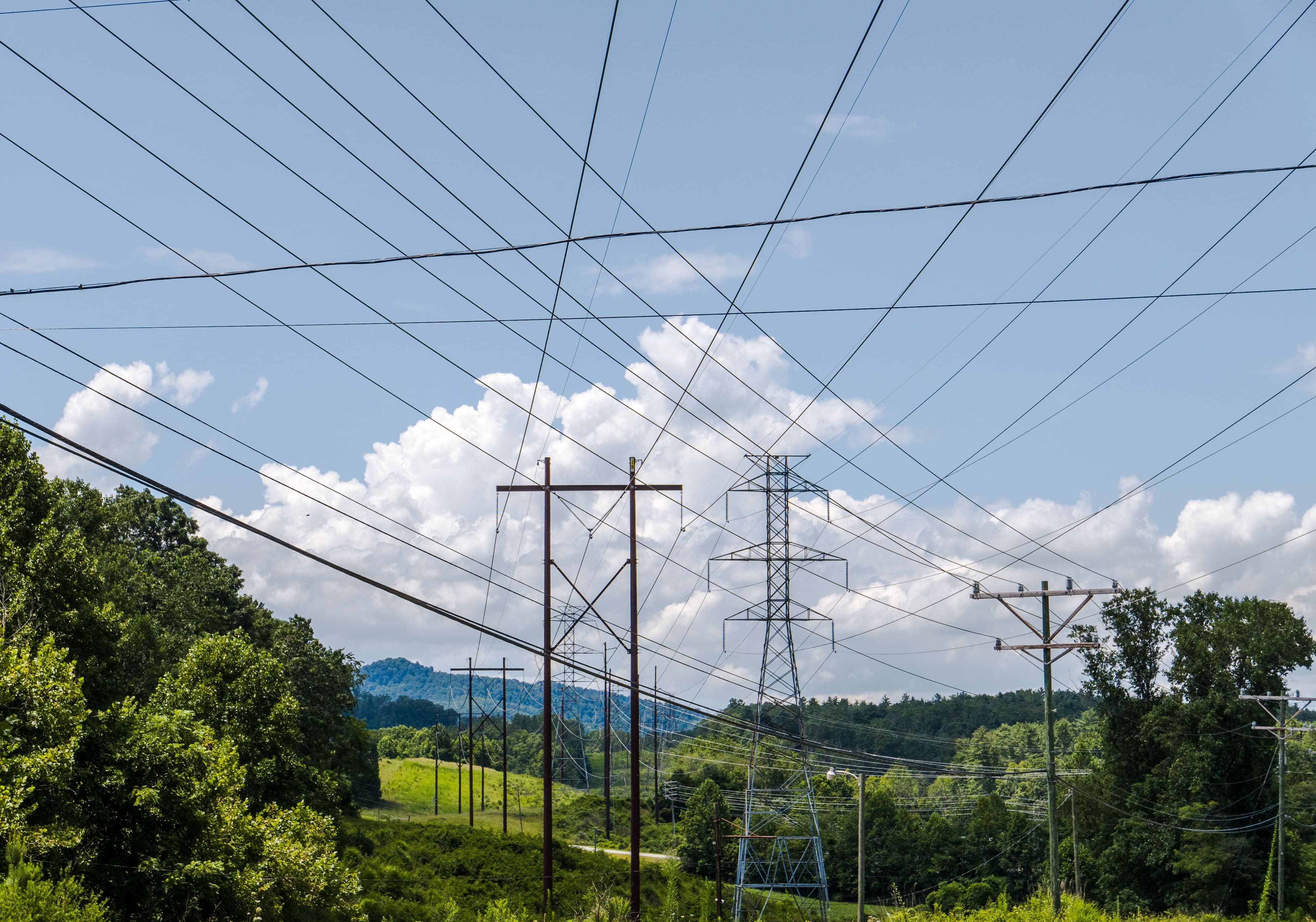 Transmission lines crossing a wide, green utility corridor.